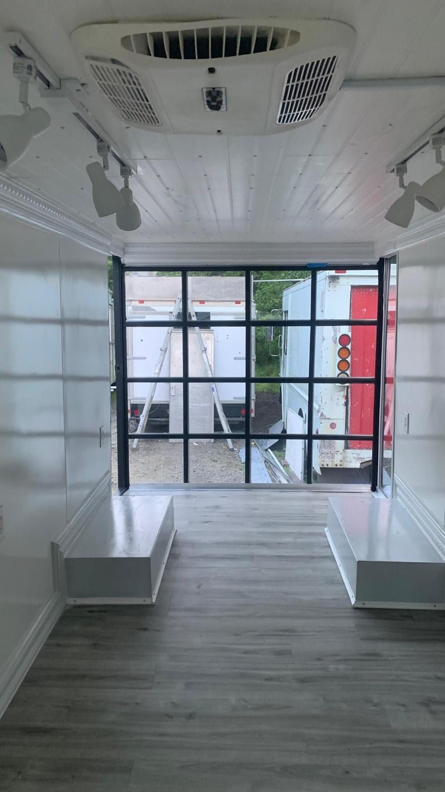 Mobile Boutique interior with white walls, track lighting and a grid glass storefront