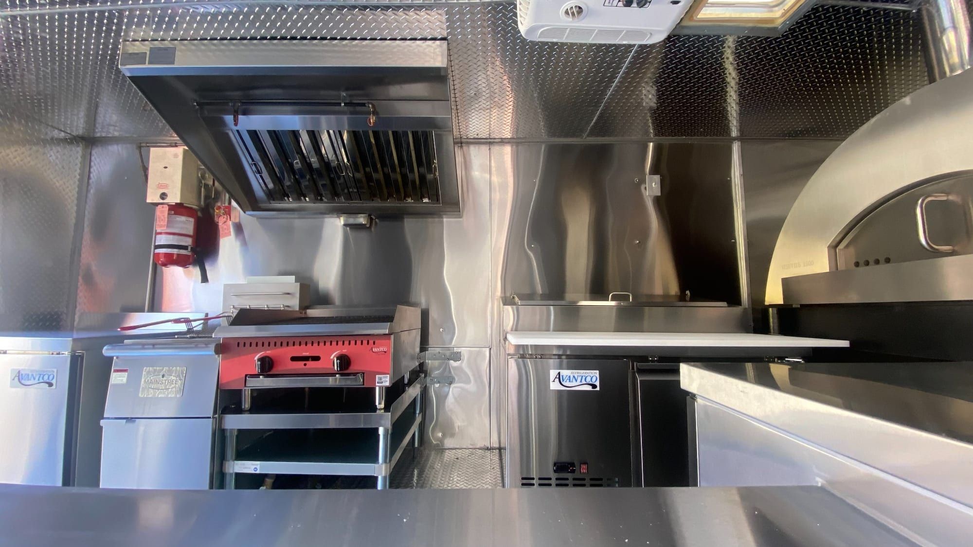 Commercial hood, charbroiler and refrigerated prep table in the pizza truck