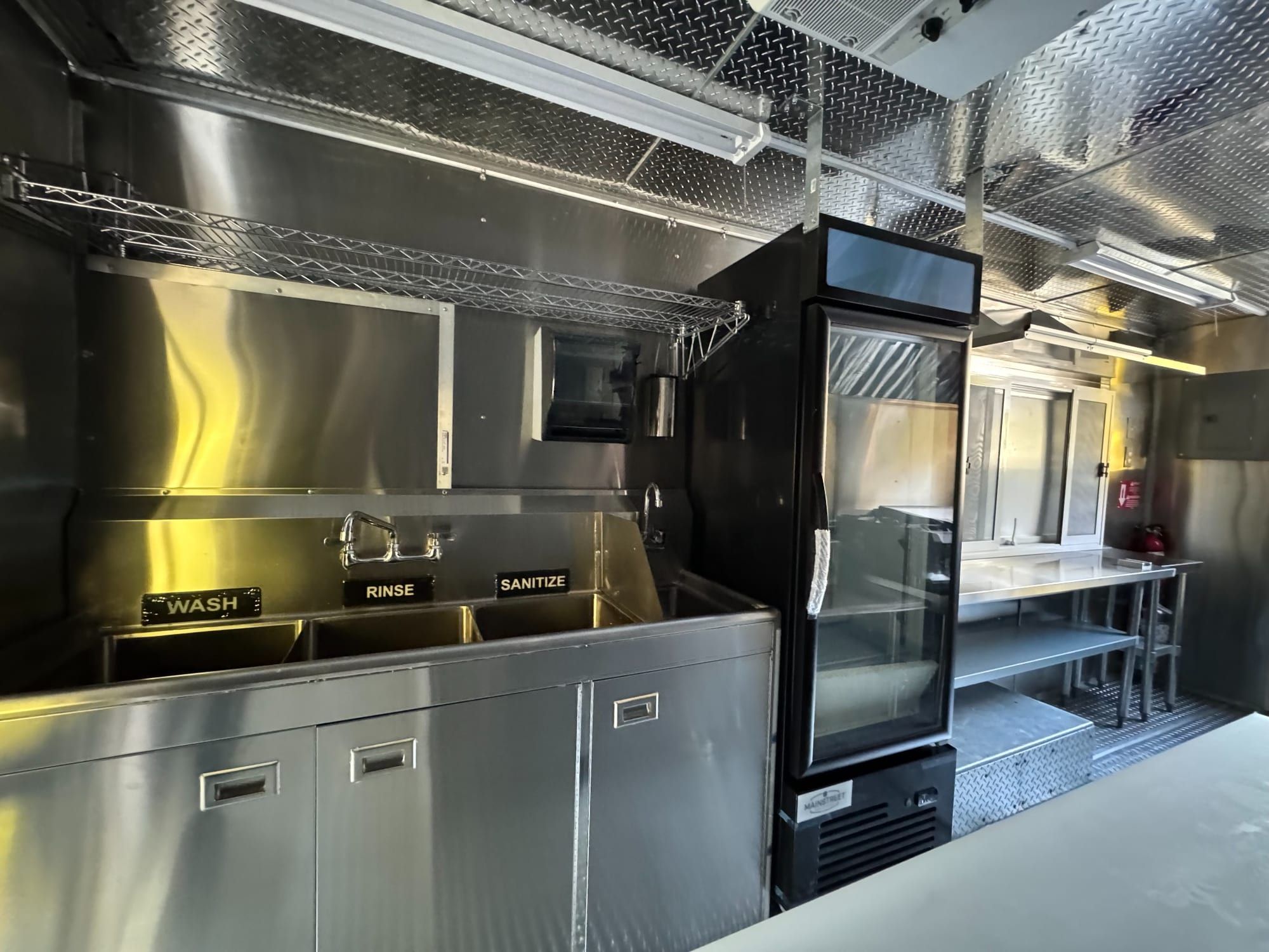 Wash, rinse and sanitize sinks and an upright refrigerator in the taco truck